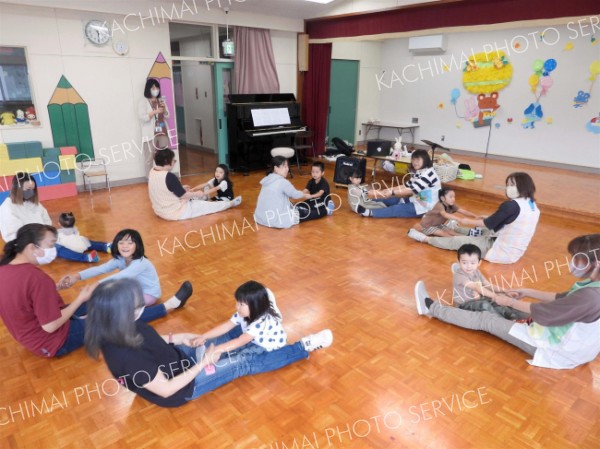 音楽に合わせて体を動かす子どもたちと西田代表（左手前）