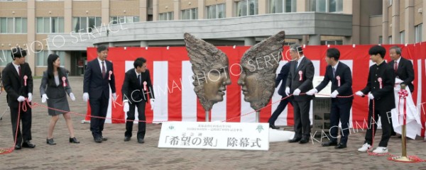 除幕された記念碑「希望の翼」とデザインした村中さん（左から４番目）（１日午前１０時１５分ごろ、助川かおる通信員撮影）