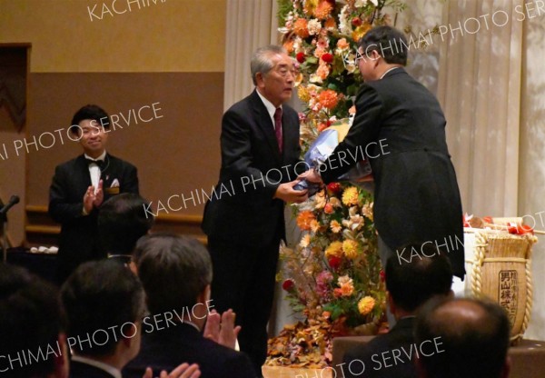 長年の貢献に感謝し、８代目社長に花束を手渡す高嶋社長