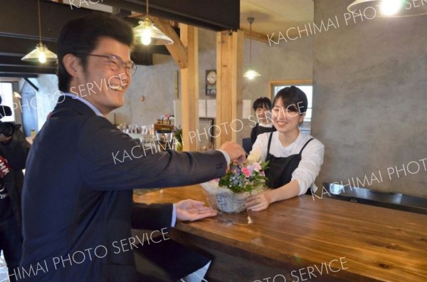 来店者から開店祝いのブーケを受け取る美月店長（右）