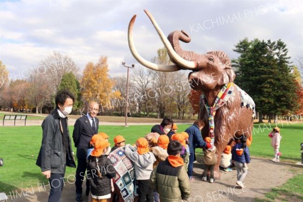 マフラーとブランケットが取り付けられたナウマンゾウの親子模型を取り囲む園児ら