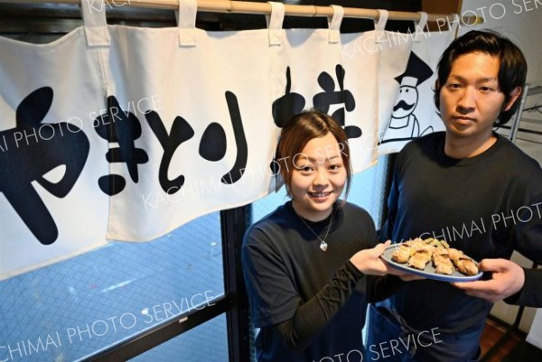 焼き上げた焼き鳥を手にする