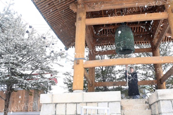 雪が降る中、「除夜の鐘」に向けて、撞木の動きを確かめる同院の池上宗恵さん。コロナ禍前につり下げていたライト（左）も今年復活し、雰囲気を盛り上げる（３１日午前９時１５分ごろ）