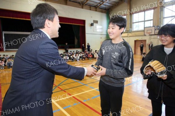 大石校長からグラブを受け取る幕別札内北小の児童会（１５日午前９時５０分ごろ、助川かおる通信員撮影）