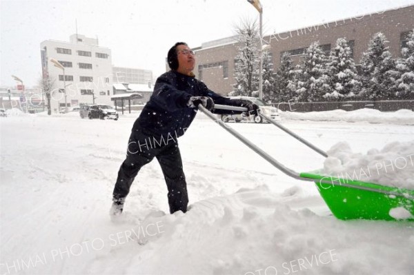 早朝から除雪作業に追われる市民ら（２３日午前９時ごろ。柳月大通本店前で）