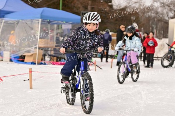 子ども用のマウンテンバイクに乗って雪上を走る子どもたち（２８日午前１０時半ごろ。金野和彦撮影）