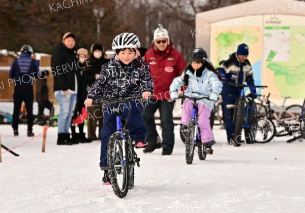 子ども用のマウンテンバイクに乗って雪上を走る子どもたち（２８日午前１０時半ごろ。金野和彦撮影）