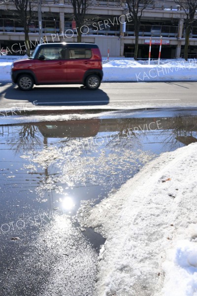 気温が上がり、車道に水たまりができた（３０日正午ごろ。市内西６南１９で。金野和彦撮影）