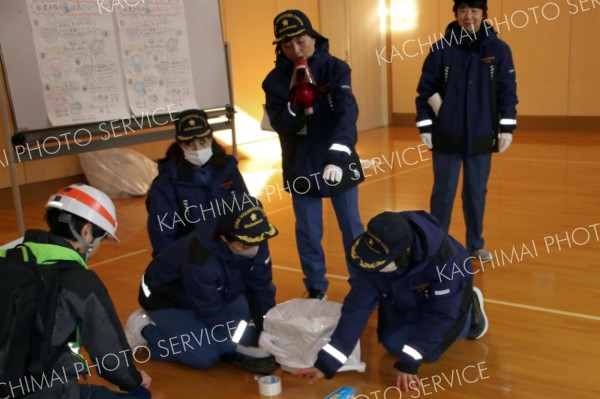 携帯トイレの使い方を実演する女性消防団員