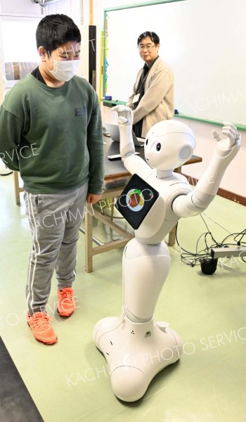 自分が作ったプログラム通りに動くロボットを見る児童