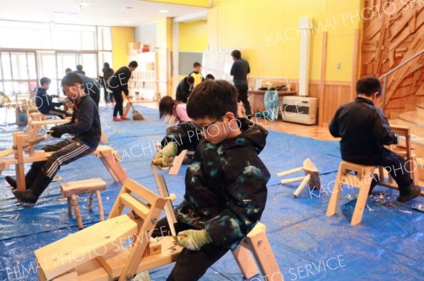 「削り馬」にまたがり、椅子の脚の製作に熱中する児童