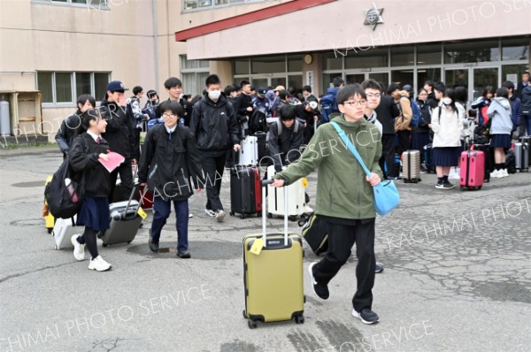 キャリーバッグを引いてバスに乗り込む帯広第二中の生徒（８日午前７時１０分ごろ、須貝拓也撮影）