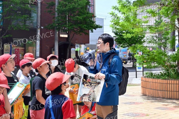 閉店となった藤丸の前で当時の様子を児童に解説する大和田学芸員（右）