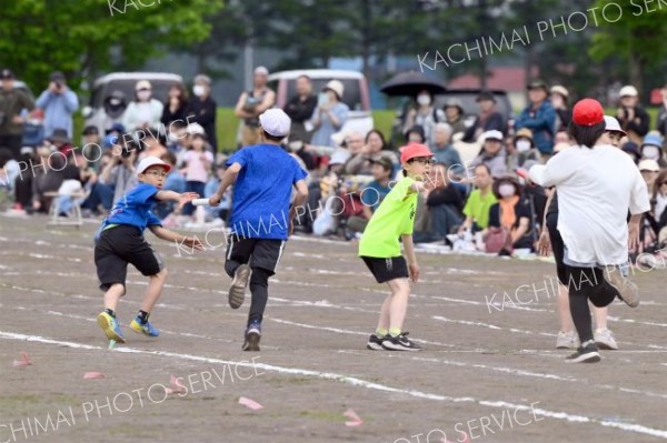 「次は俺に任せろ」－。５・６年生のリレーで、競り合う子どもたち（８日、更別小学校。金野和彦撮影）