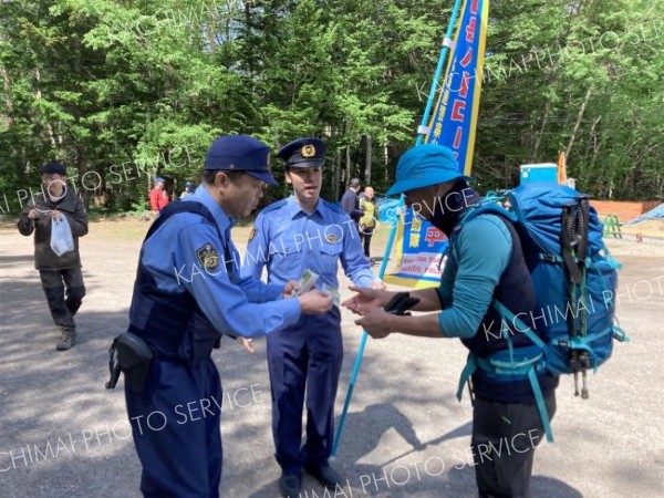 登山者（右）に山岳遭難やヒグマとの事故防止を呼び掛ける本別署員ら