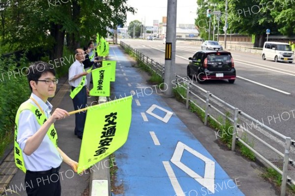 旗を掲げて運転手に安全運転を促す職員