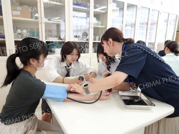 血圧測定を体験する高校生