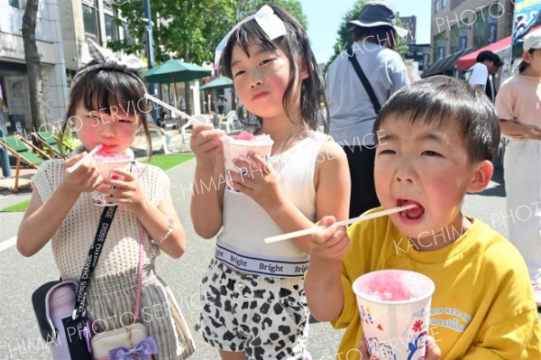 今季初の猛暑日となった帯広で、汗をかきながらかき氷を食べる子どもたち（２１日午後１時２５分ごろ、帯広まちなか歩行者天国で）