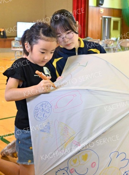 傘いっぱいに絵を描く帯広聾学校の児童（左）と見守る幕別清陵高校の生徒