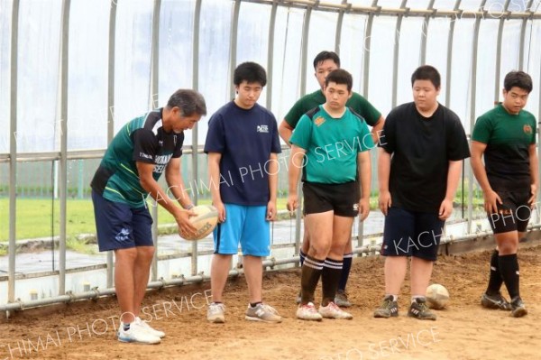 中学生にラグビーボールの蹴り方を教える田村朋弘監督（左）