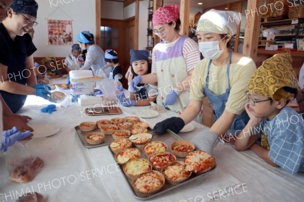 焼きあがった「ピザ風総菜パン」を運ぶ吉間さん（右から２人目）