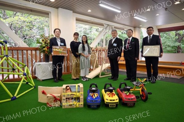 寄付を受けたおもちゃを前に並ぶ、お披露目式に出席した名付け親の今井さん（左から３人目）や広瀬容孝教育長（同４人目）ら