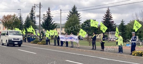 黄色い旗を持って交通安全を呼び掛ける参加者たち