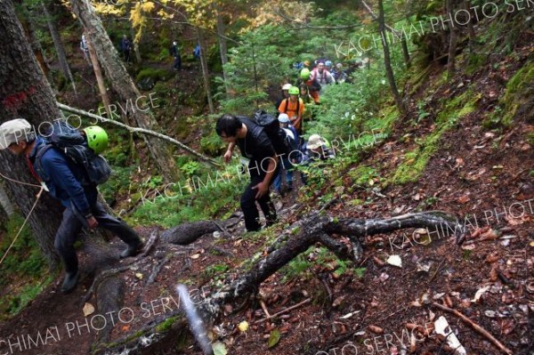 溶岩が積み重なった急な登山道を登る参加者ら