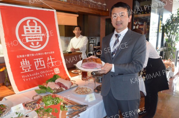 「豊西牛」のお披露目の場となった試食会で、肉を手にするトヨニシファームの小倉修二社長（１３年５月１３日）