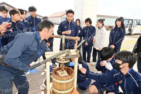 手動の圧搾機で作ったブドウジュースを試飲する生徒