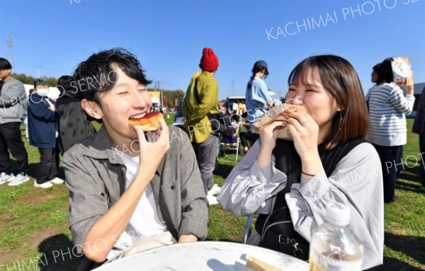 買い求めたあんパンを頬張る来場客（１２日午１１時４０分、道の駅おとふけで。塩原真撮影）