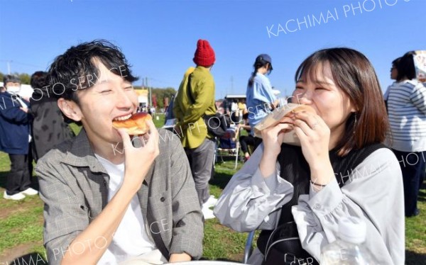 青空の下であんパンを頬張りにっこり笑顔