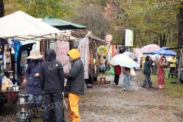 あいにくの雨の中、傘を差して会場内を回る来場者たち（１９日午前１１時半ごろ、助川かおる通信員撮影）