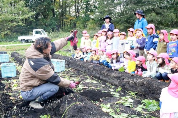 鈴鹿さん（左）の説明を聞き、収穫の仕方を学ぶ園児たち