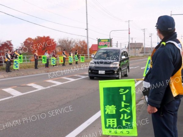 シートベルト着用と書かれた旗で安全運転を呼び掛ける会員たち