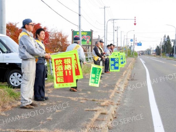 国道沿いで旗を掲げ、安全運転を呼び掛ける会員たち