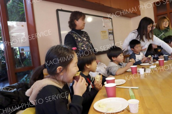 自分で作ったバターをイモに塗り食べる子どもたち