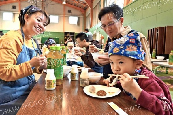 完成した餅を味わう家族（金野和彦撮影）