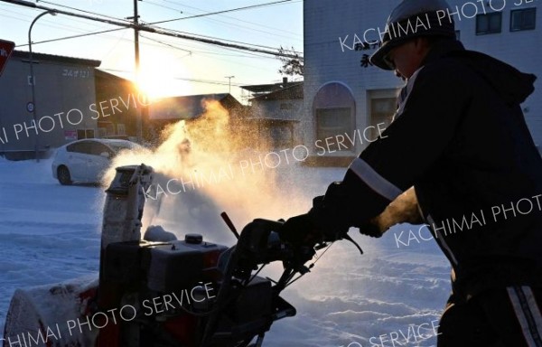 元旦は雪かきからスタート－。初日の出に照らされ、除雪に追われる市民（１日、帯広市内で）