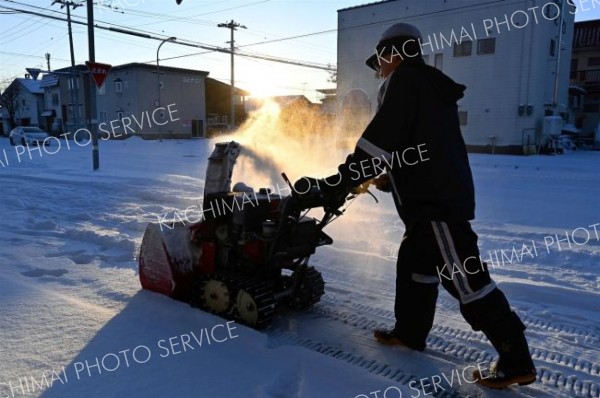 元旦は雪かきからスタート―。初日の出に照らされ、除雪に追われる市民（１日、帯広市内で）