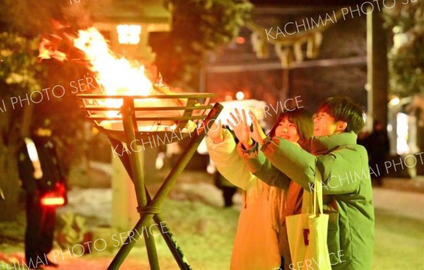 参道を照らす炎が参拝者の凍えた手を温めた（１日、帯廣神社で。金野和彦撮影）