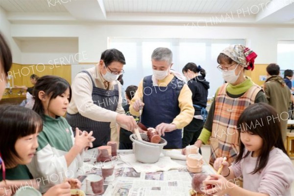 自作した素焼きの器に色付けする参加者