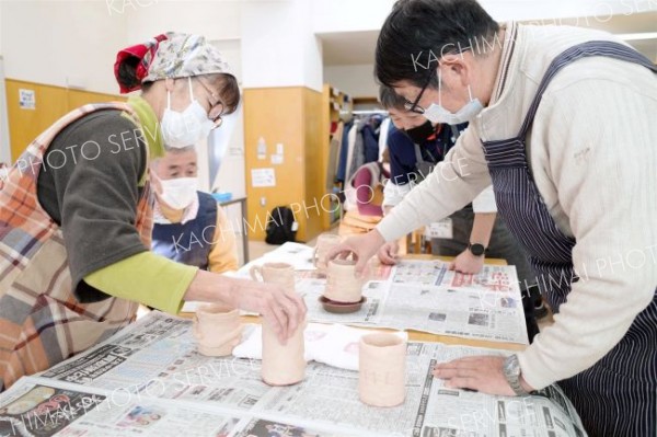 自作した素焼きの器に色付けする参加者