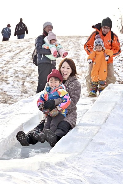 沼の氷を切り出して作った滑り台で楽しむ親子連れ（１９日午前１０時１５分ごろ、塩原真撮影）