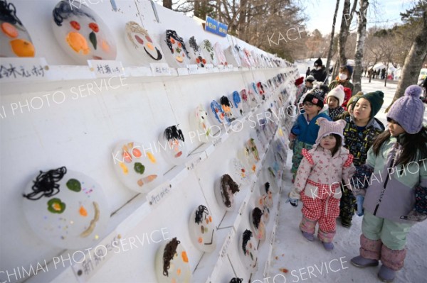 表情豊かな氷のお面を見る子どもたち