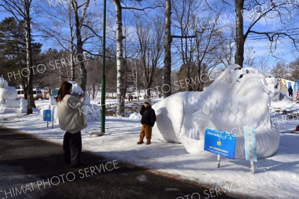 帯広市長賞を受賞した南幕雪像生産組合の「鯉」の前で記念撮影をする来場者（３１日午前１０時ごろ）