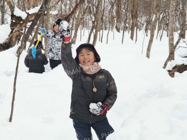 雪中ジャガイモ堀りでジャガイモを見つけた子ども