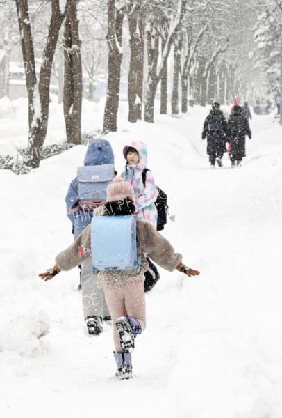 雪が降る中、走って登校する児童ら（６日午前８時５分ごろ、幕別札内南小付近で、村瀬恵理子撮影）