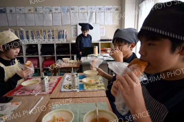 揚げパンをおいしそうに食べる下音小の６年生ら