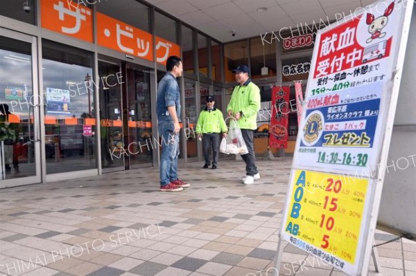 店舗前でポケットティッシュを手に献血を呼び掛ける会員
